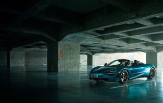 mclaren 720 spyder front 3:4 A sleek blue McLaren 720s coupe is parked in a dimly-lit, empty concrete parking garage. The car is positioned near pillars marked with orange numbers 3 and 5, with light streaming in from the right side, illuminating the vehicle's contours as if enhanced by meticulous photographic retouching.