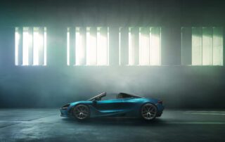 mclaren 720 spyder side Side profile of the McLaren 720S Spyder, roof down, beneath a striped light installation.