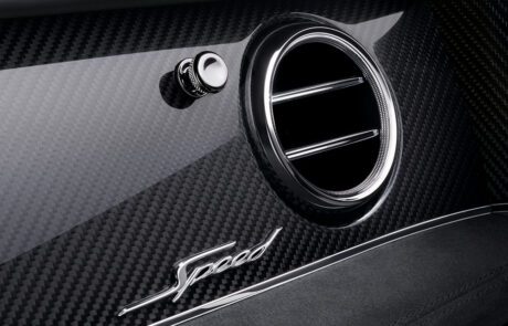 Close-up of a Bentley Bentayga Speed's interior featuring a circular air vent, a "Speed" emblem, and a sleek carbon fiber finish. The design is modern and elegant, emphasizing high performance and luxury with high-end retouching for an impeccable look.