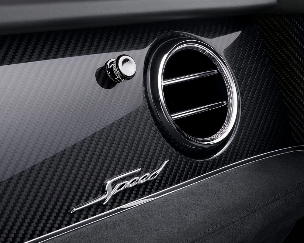 Close-up of a Bentley Bentayga Speed's interior featuring a circular air vent, a "Speed" emblem, and a sleek carbon fiber finish. The design is modern and elegant, emphasizing high performance and luxury with high-end retouching for an impeccable look.