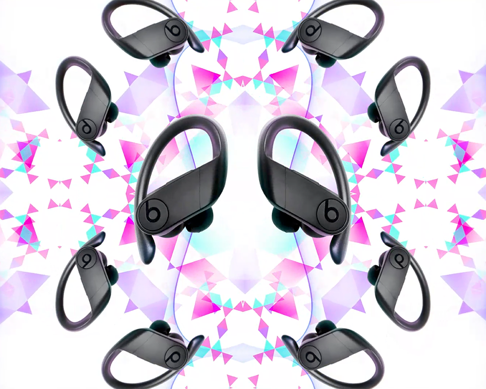 A symmetrical pattern with wireless earbuds. Eight pairs of black Beats headphones with over-ear hooks are arranged in a kaleidoscopic design. The background features an abstract geometric pattern with triangles in shades of pink, purple, and white, resembling the logo from Three network.