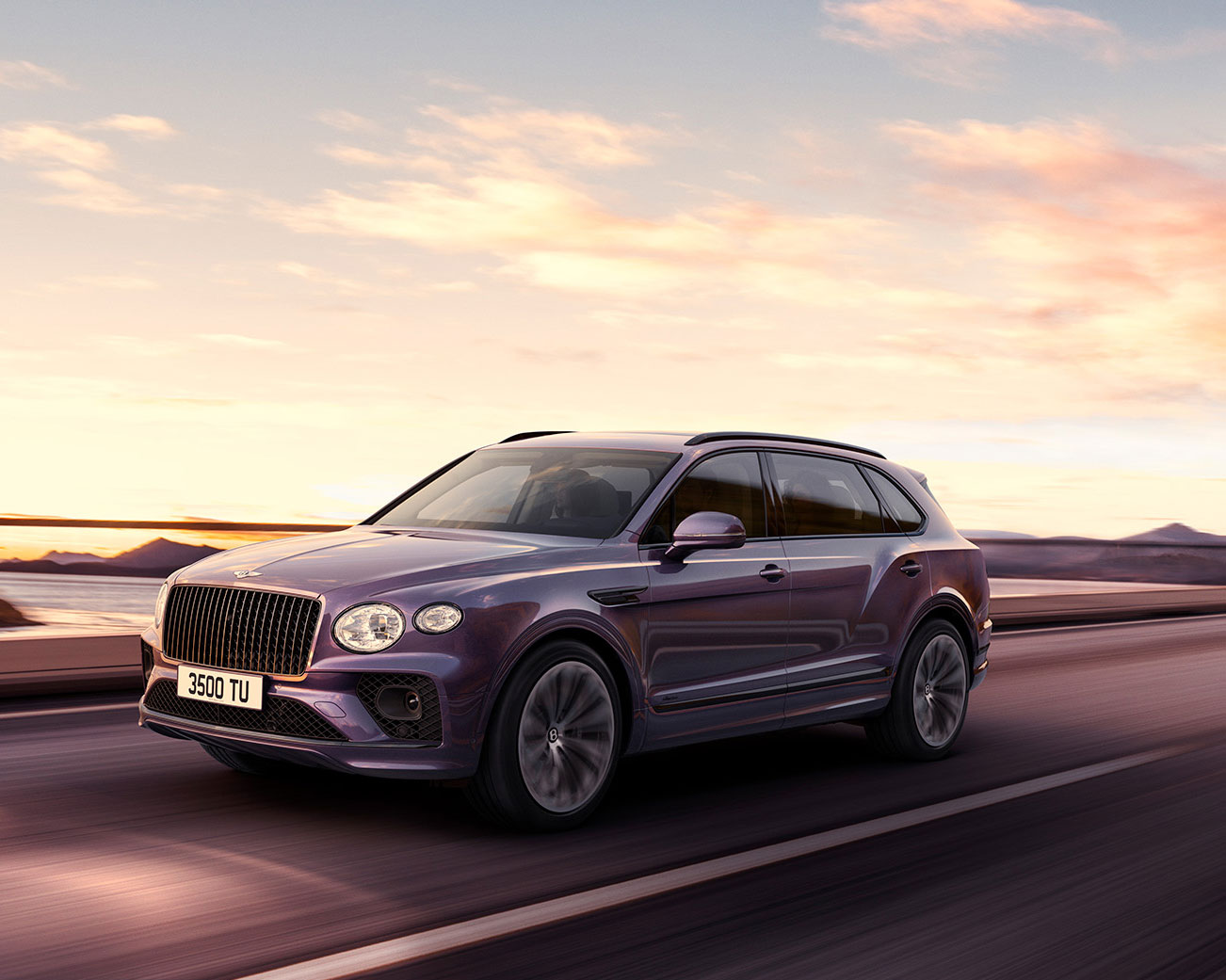 A CGI depiction of a purple Bentley Bentayga Extended Wheelbase SUV drives on a highway at sunset, set against a scenic background of mountains and a colorful sky. The vehicle boasts sleek design features, including a distinct front grille and modern headlights, with license plate "3500 TU" visible.