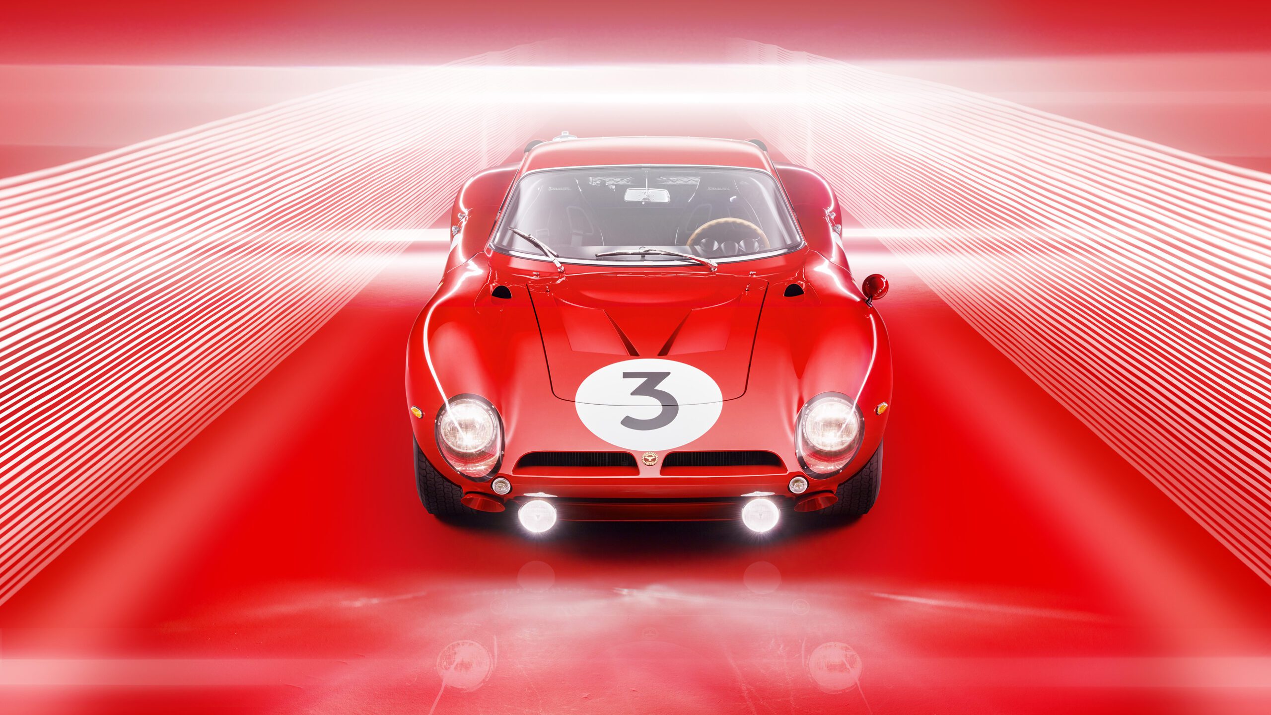 A retouched red classic racing car, likely a Bizzarrini 5300 GT Corsa Rossa, with the number 3 displayed on its hood is illuminated under dramatic lighting. The background features red lines and a light gradient that create a dynamic, tunnel-like effect.