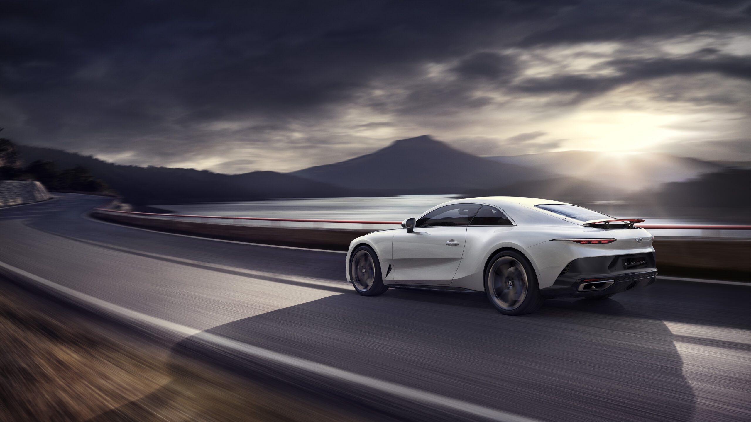 A sleek white Bentley Batur hypercar speeds down a winding road beside a lake, with mountains in the background and a dramatic, cloudy sky illuminated by the setting sun. The car moves towards a curve, highlighting its dynamic and fast nature as if crafted by a CGI artist.