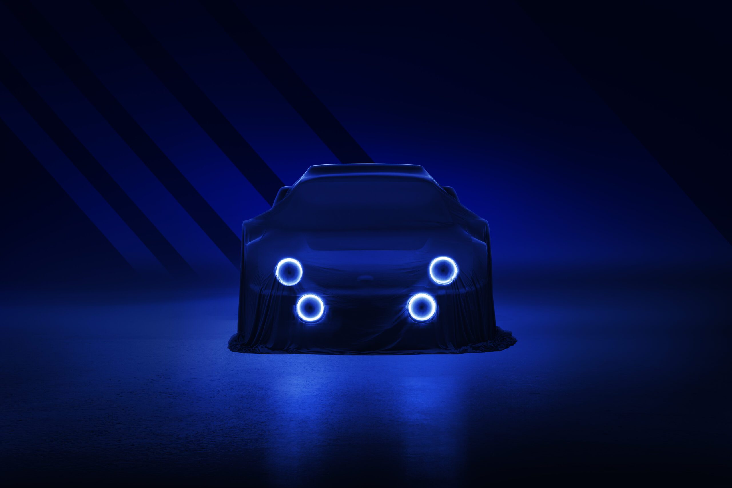 A dark and sleek image of a Ford RS2000 DRVN draped in a cloth, partially illuminated by four glowing circular lights on its front. The overall scene is bathed in deep blue tones, giving a futuristic and mysterious ambiance reminiscent of a car retoucher’s meticulous work.