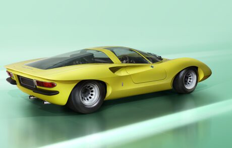 A sleek, vintage yellow sports car with a low, aerodynamic design. It features a curvy body reminiscent of the Alfa Romeo 33, large rear wheels, and a transparent roof, set against a smooth, light-green background. The car has round tail lights and a dual exhaust system.