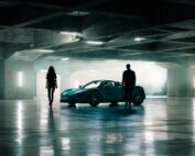 A man and woman stand beside the McLaren 720S Spyder in a dramatically lit underground car park.
