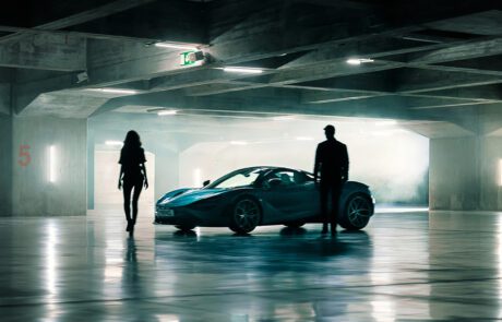 A man and woman stand beside the McLaren 720S Spyder in a dramatically lit underground car park.