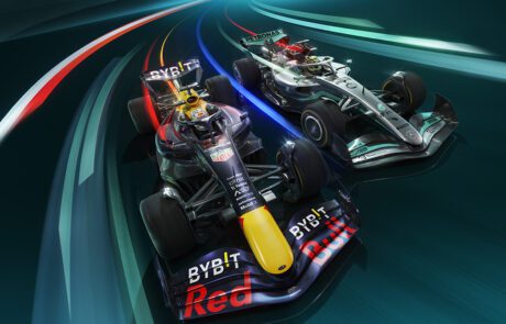 Two Formula 1 cars race side by side, leaving streaks of light behind them in a CGI masterpiece. The car on the left is predominantly dark blue with red and yellow accents, while the car on the right is silver and black. Both cars appear to be moving at high speed on a curved track, as seen on Sky F1.