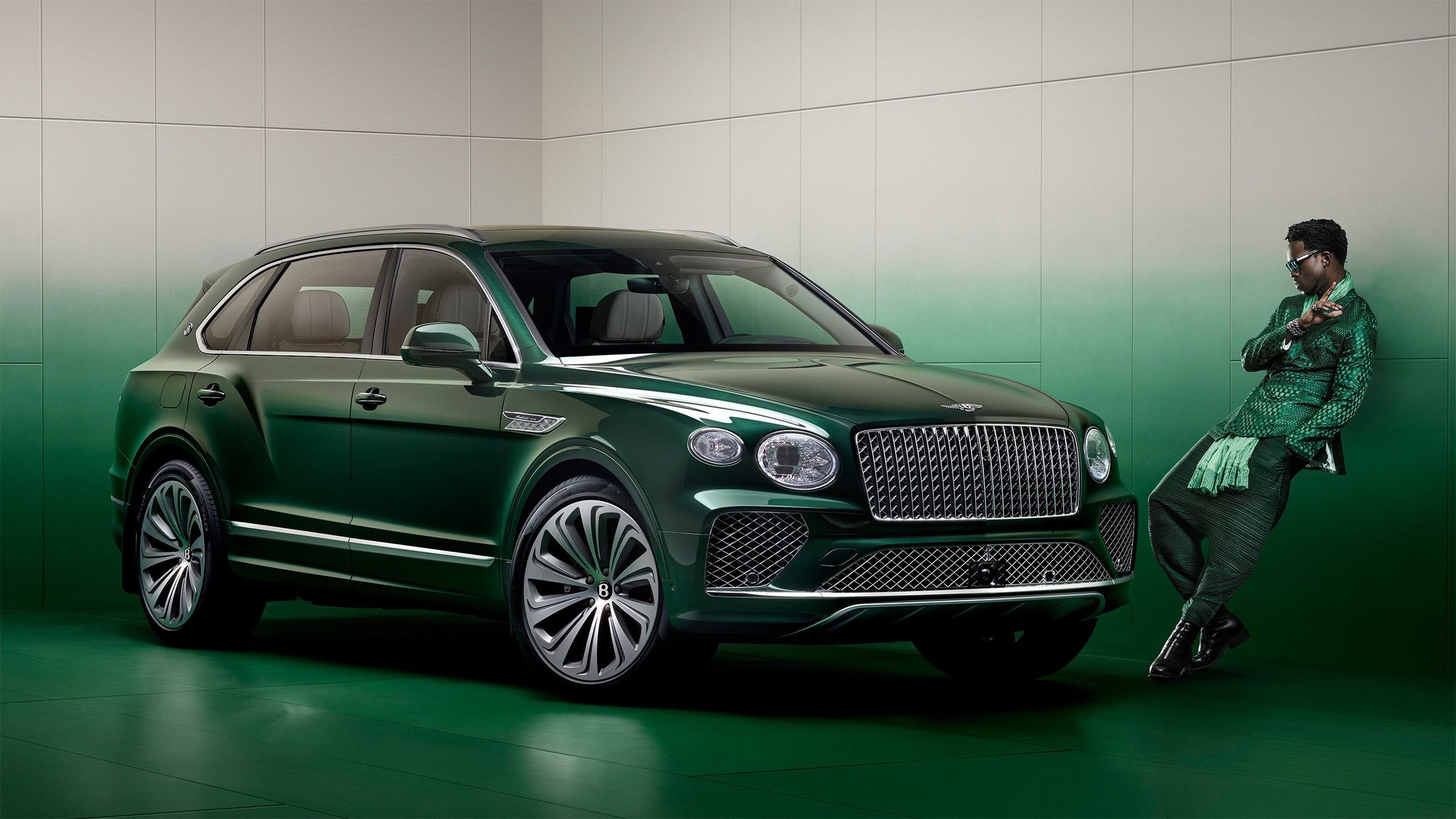A stylish person dressed in green leans against a wall next to a green luxury Bentley SUV, both set against a matching green-and-white gradient background.