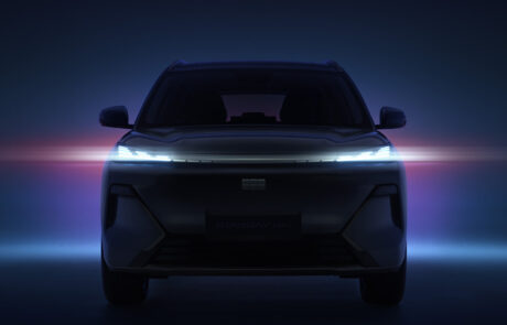 A dark, front-facing car with illuminated LED headlamps glows against a blue and pink gradient background, creating a futuristic atmosphere.