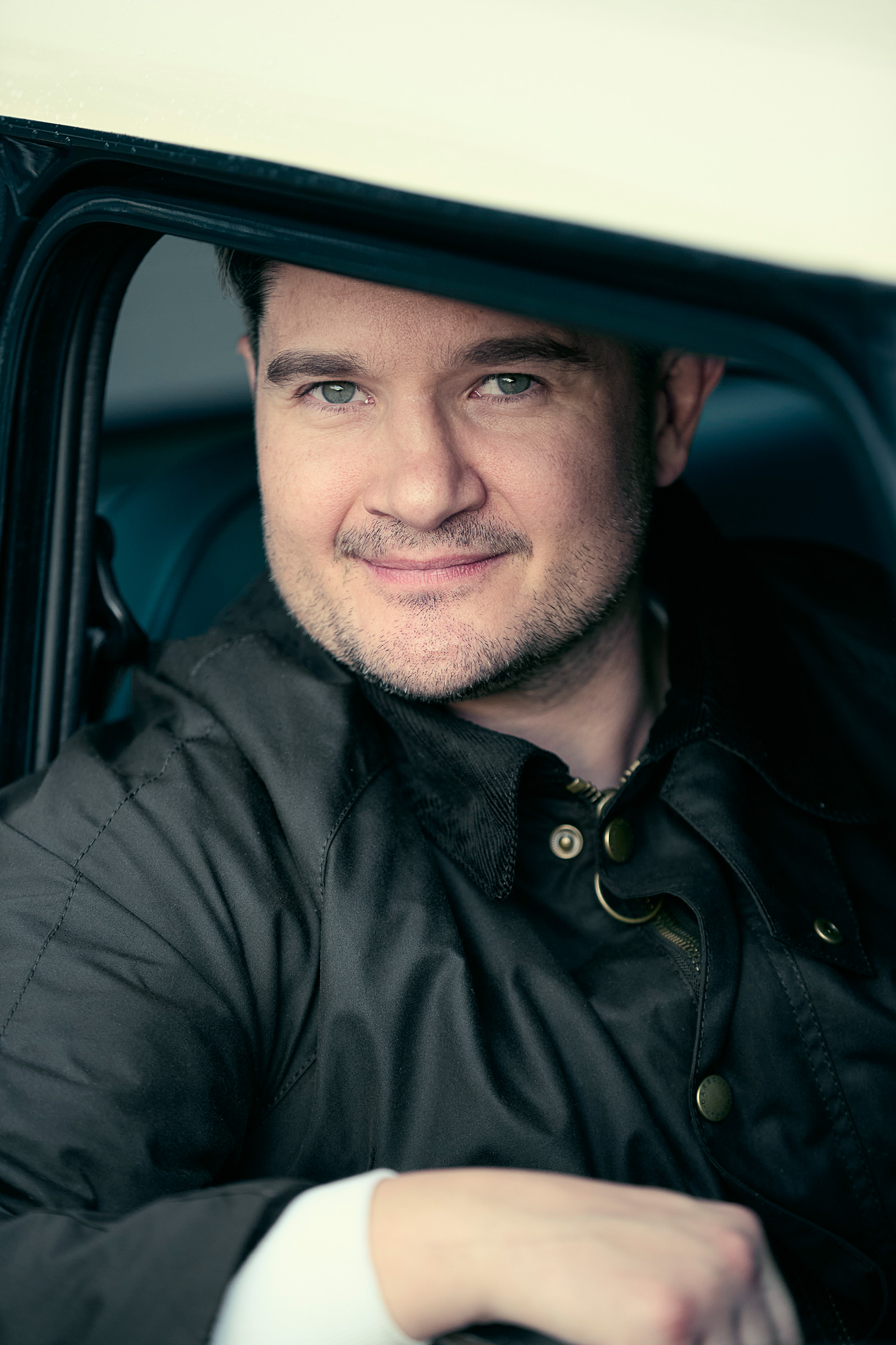 charlie-cooper-portrait-mini-cooper-shoot Charlie Cooper, grandson of John Cooper, smiles through the open window of a new Mini Cooper Grand Prix on a rainy day.