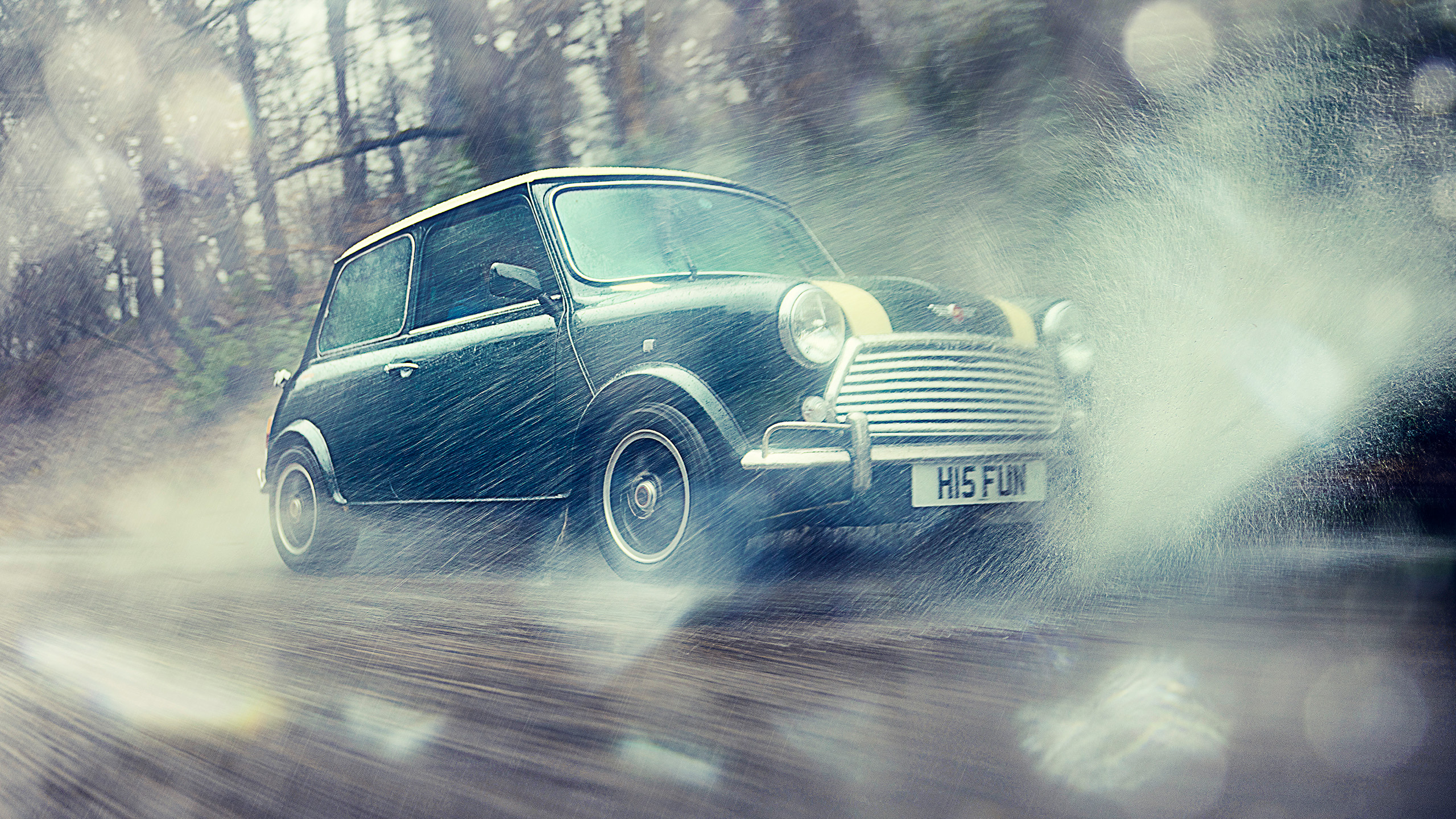 mini-cooper-grand-prix-cooper-cars-front-splash-action A Mini Cooper Grand Prix drives fast through rain and spray on a wooded road, front three-quarter view.