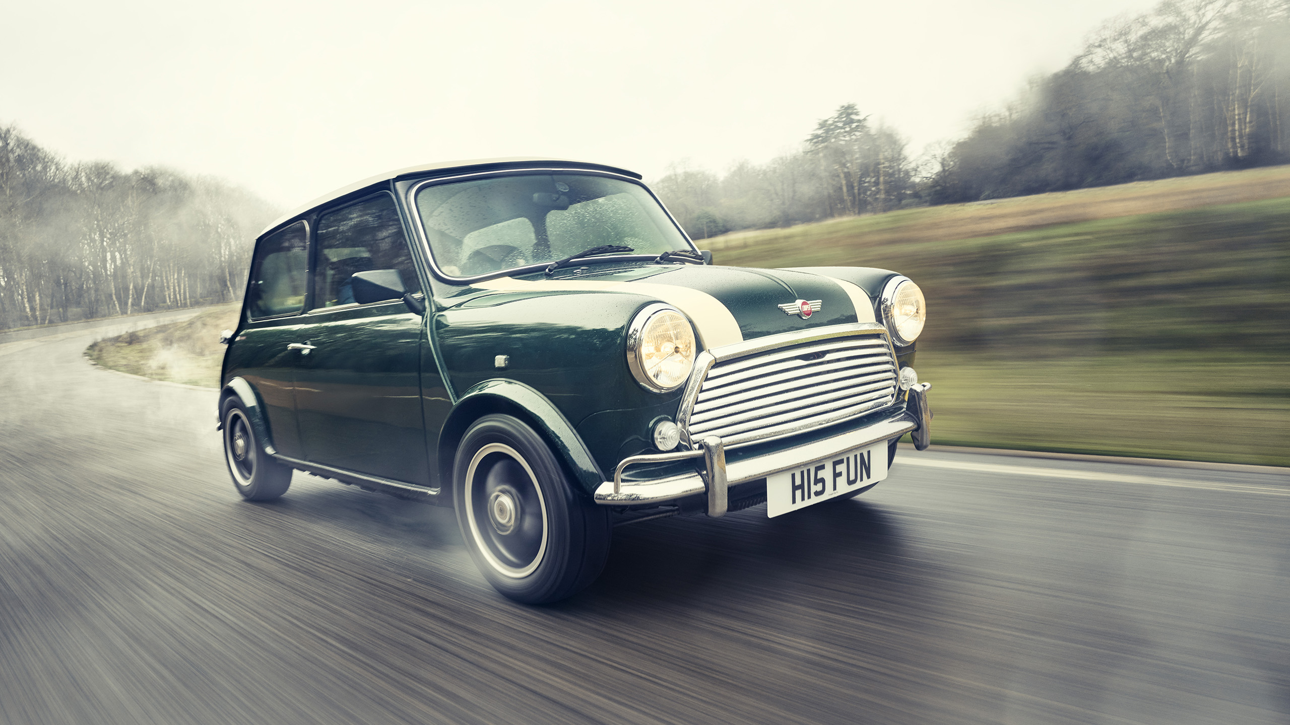 mini-cooper-grand-prix-cooper-cars-front-three-quarter-drive Dynamic front three-quarter view of a Mini Cooper Grand Prix in motion on a foggy country road.