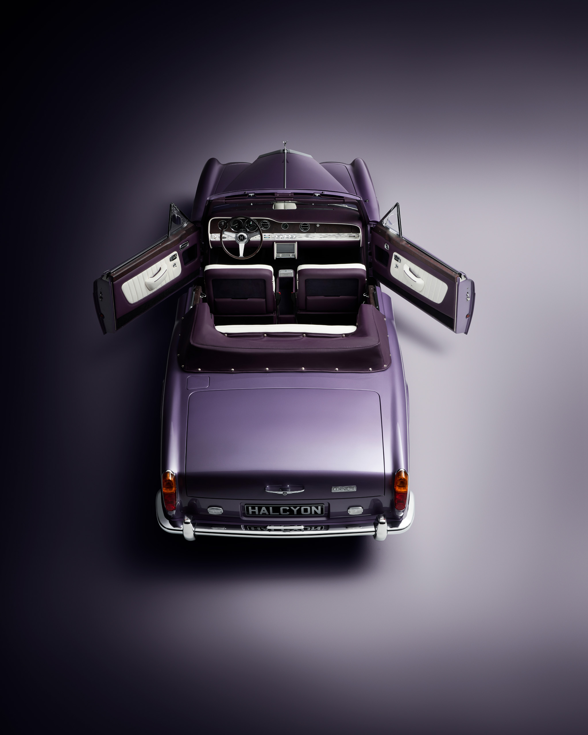 halcyon-electric-rolls-royce-corniche-top-down-doors-open.jpg Overhead view of the Halcyon electric Rolls-Royce Corniche with both doors open, showing the wood veneer dashboard and white and aubergine leather interior.