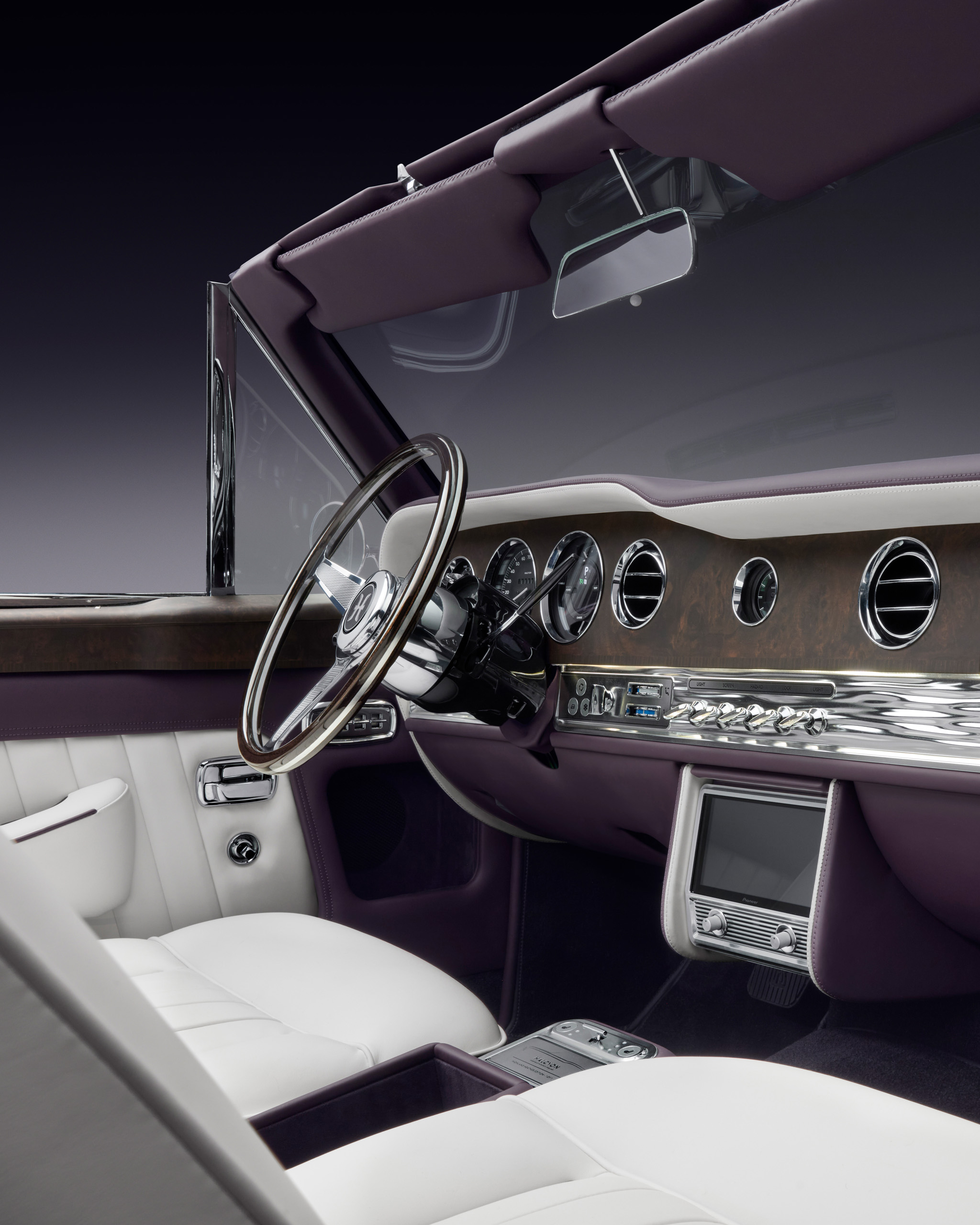 1354_SC_Halcyon_STU_06_MainInterior_v3a_Media_4x5 Wide interior view of the Halcyon electric Rolls-Royce Corniche, showing the wood veneer dashboard, chrome switchgear, white leather seats and integrated media screen.