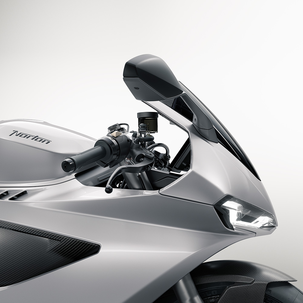 Close-up of a sleek, silver Norton motorbike showcasing its angular wing mirror, handlebars, and modern headlamp against a plain, light background.