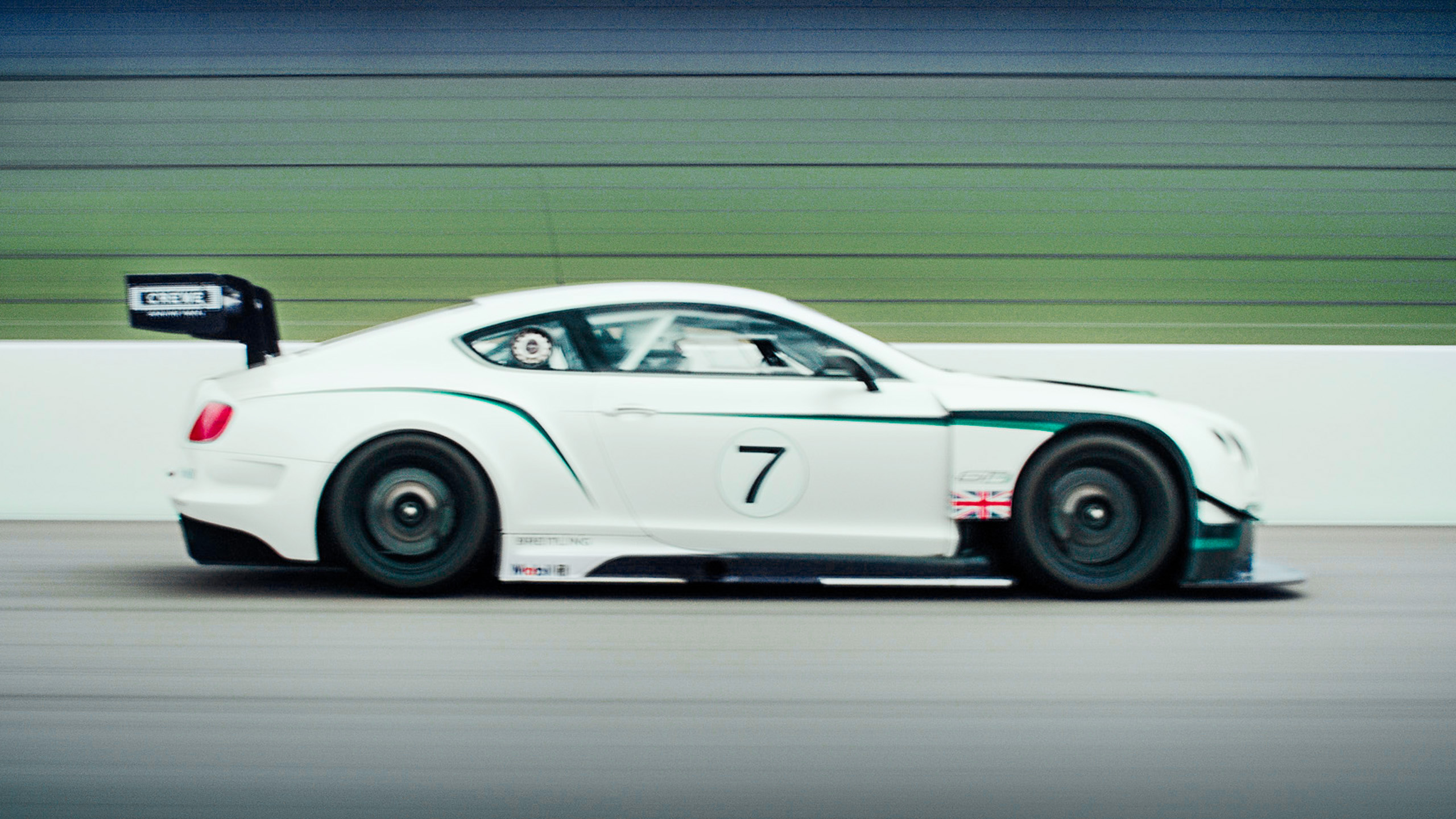 bentley-continental-gt3-race-car-side-profile-number-7 A white Bentley Continental GT3 race car with green livery and number 7, captured side-on at speed on the racetrack.