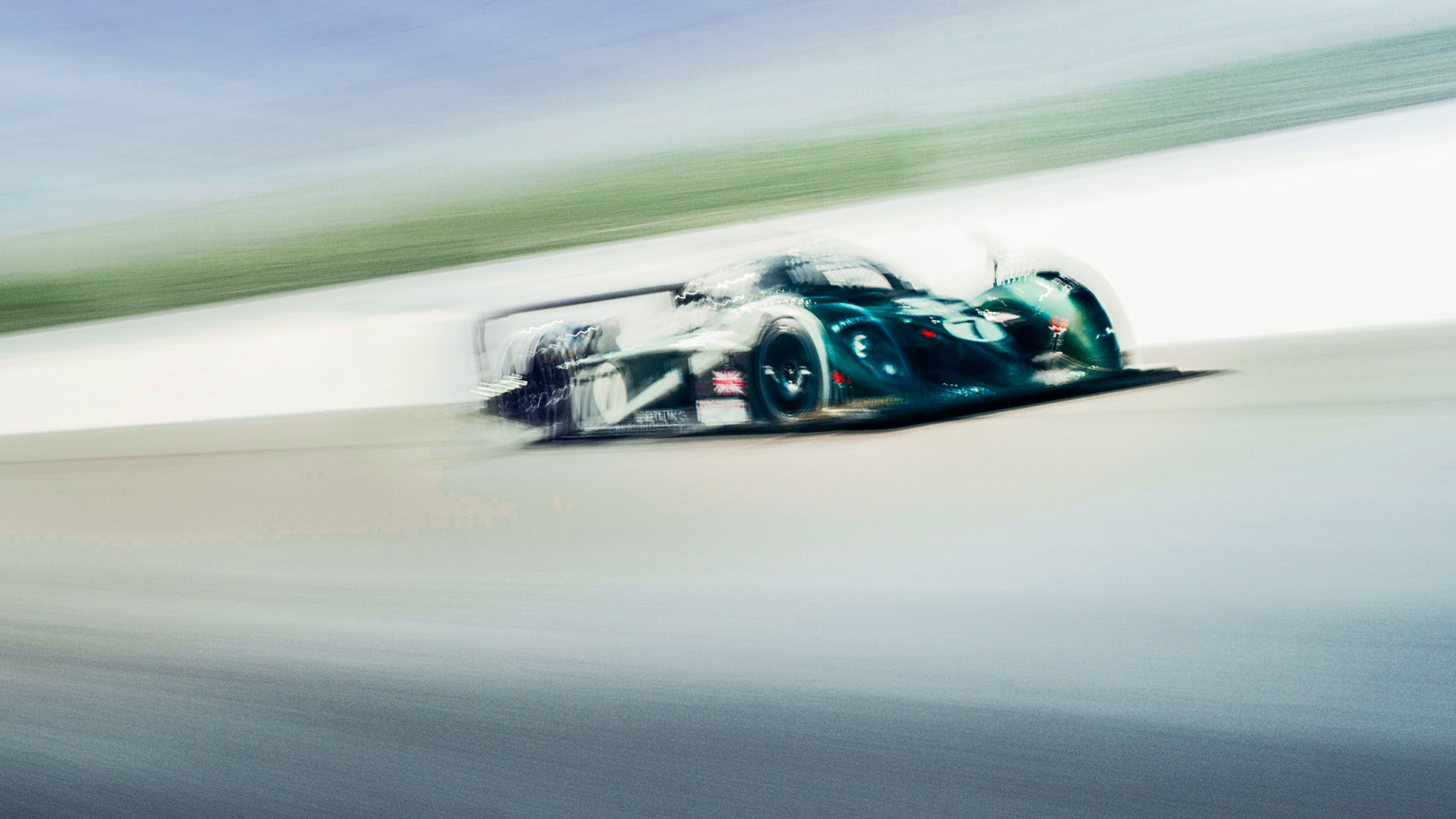 bentley-speed-8-le-mans-prototype-cornering-front-quarter A green Bentley Speed 8 Le Mans prototype racing car cornering at speed, motion blur emphasising its curved bodywork and number 7 livery.