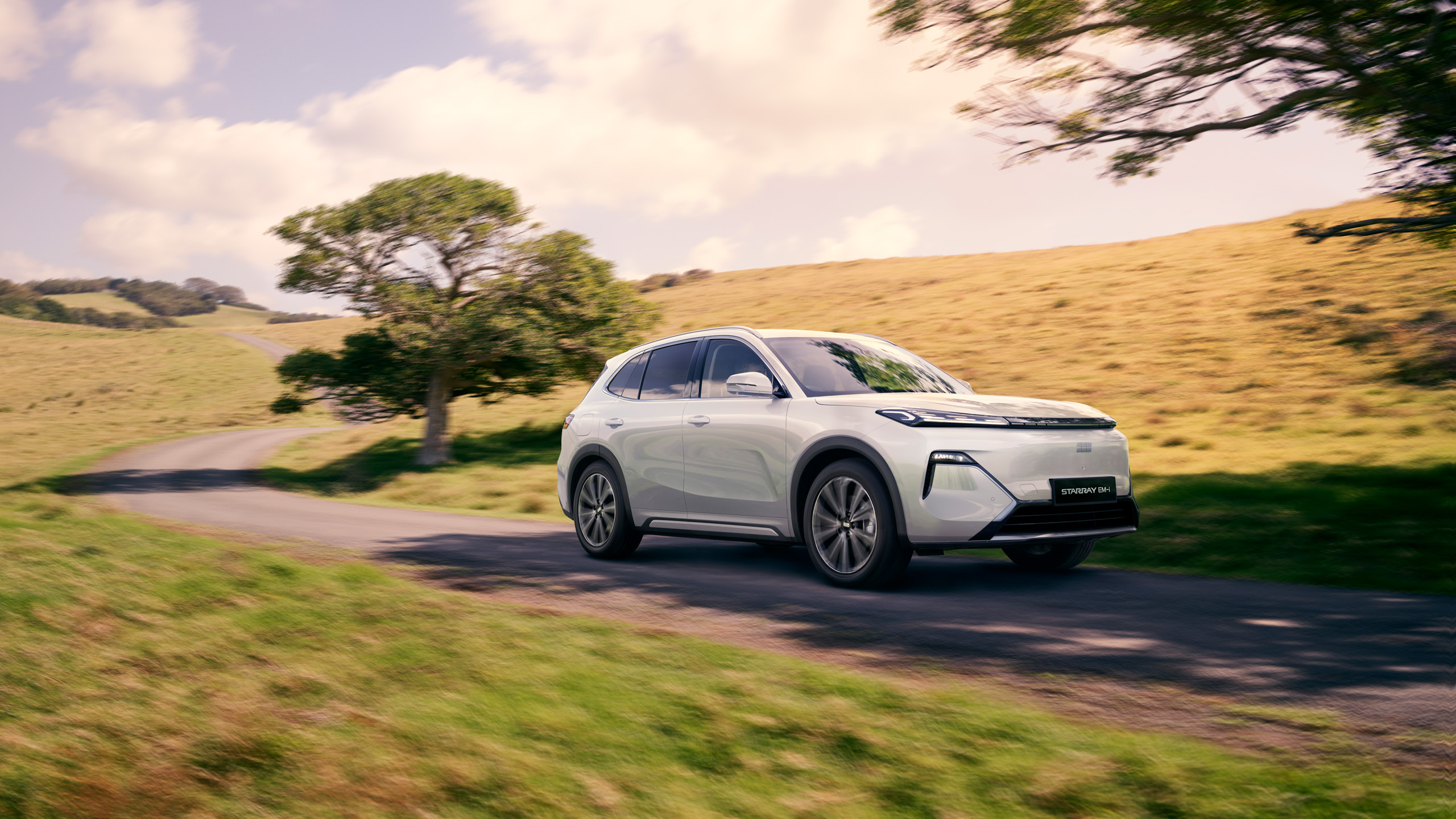 geely-starray-emi-front-three-quarter-country-lane Front three-quarter view of the Geely Starray EM-i driving along a tree-lined Australian country lane.