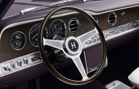 Close-up of the Halcyon dashboard and steering wheel, featuring the custom "H" badge, analogue-style dials and wood veneer trim.