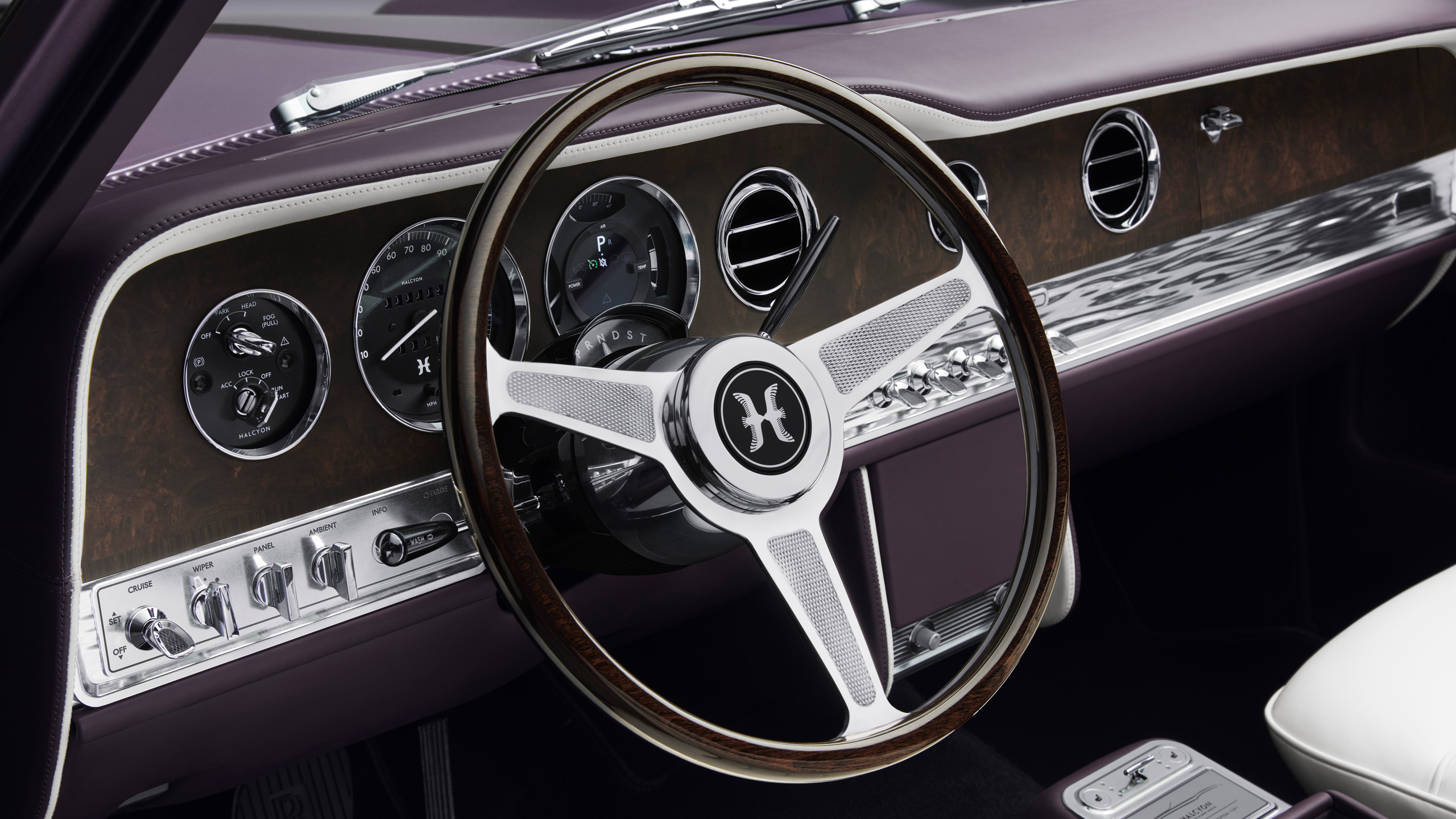 Close-up of the Halcyon dashboard and steering wheel, featuring the custom "H" badge, analogue-style dials and wood veneer trim.