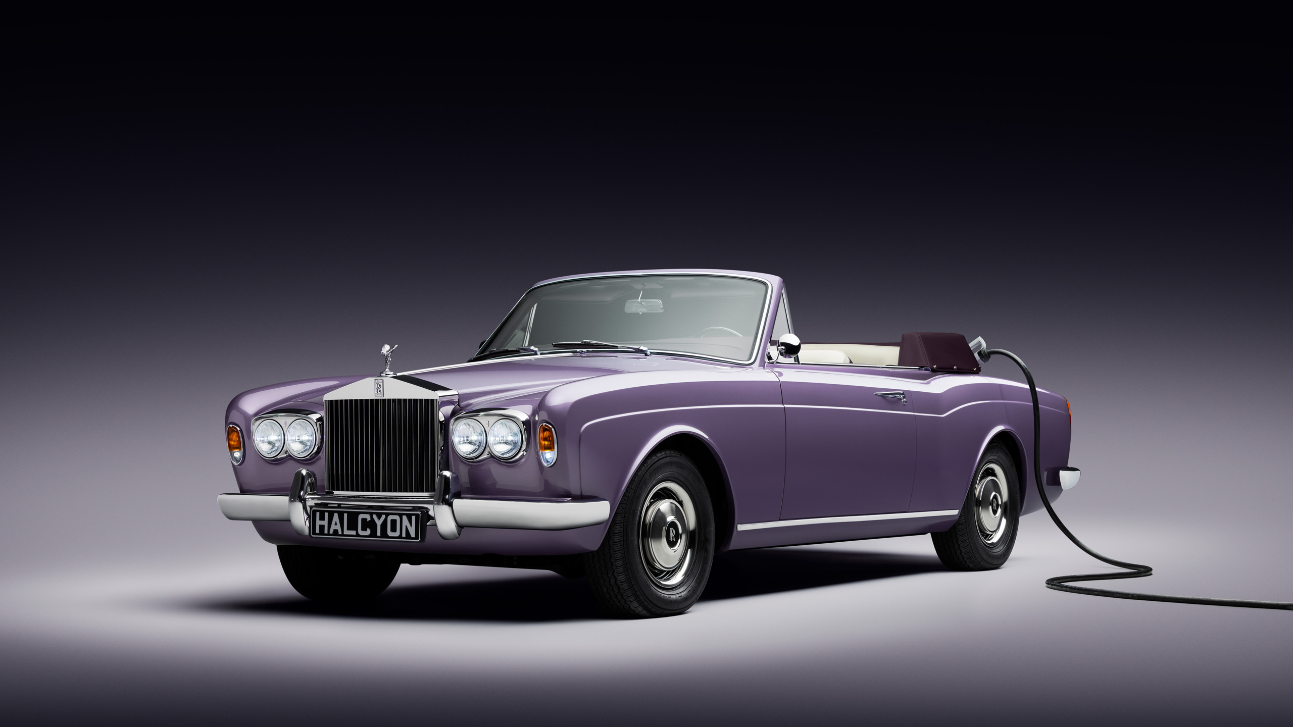 halcyon-electric-rolls-royce-corniche-front-three-quarter-charging Front three-quarter view of the Halcyon electric Rolls-Royce Corniche in the studio, charging cable connected at the rear wing.
